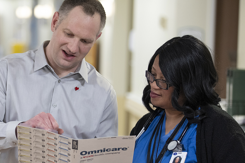Jim Andros pointing to an Omnicare Medication pack with an Omnicare professional